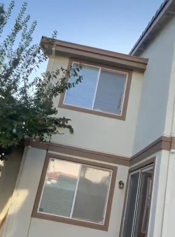 Back corner of a two-story house after washing, light walls with brown trim around the upper and lower windows